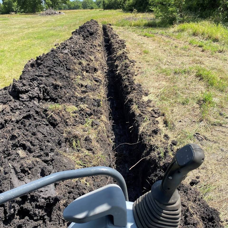Trenching machine cutting a drainage line